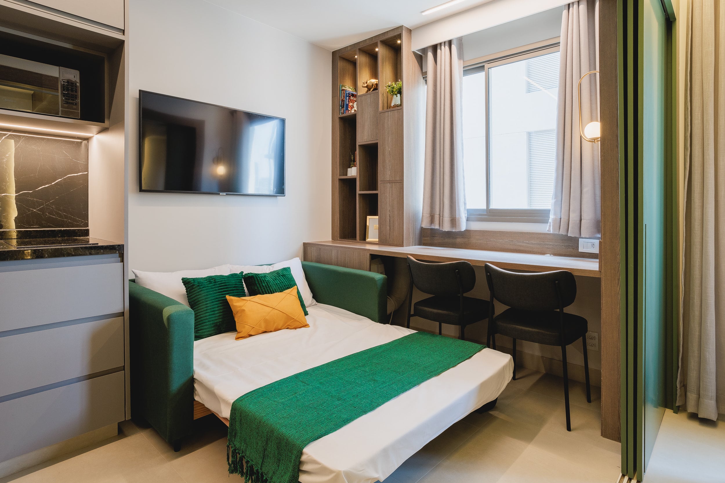 O mesmo espaço em modo dormir, com o sofá-cama aberto junto à bancada