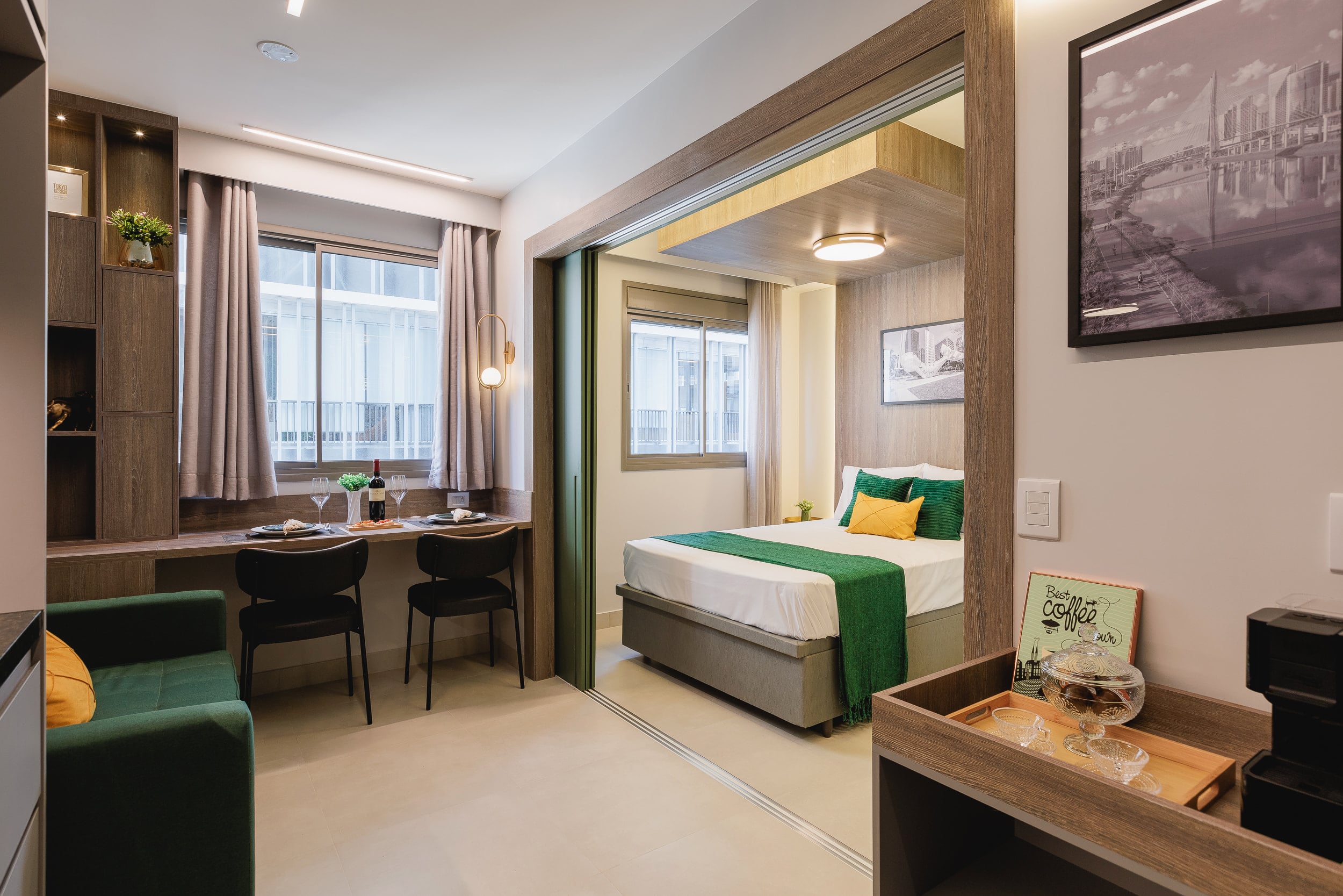 Cama de casal com manta verde e a bancada de trabalho refletida no espelho