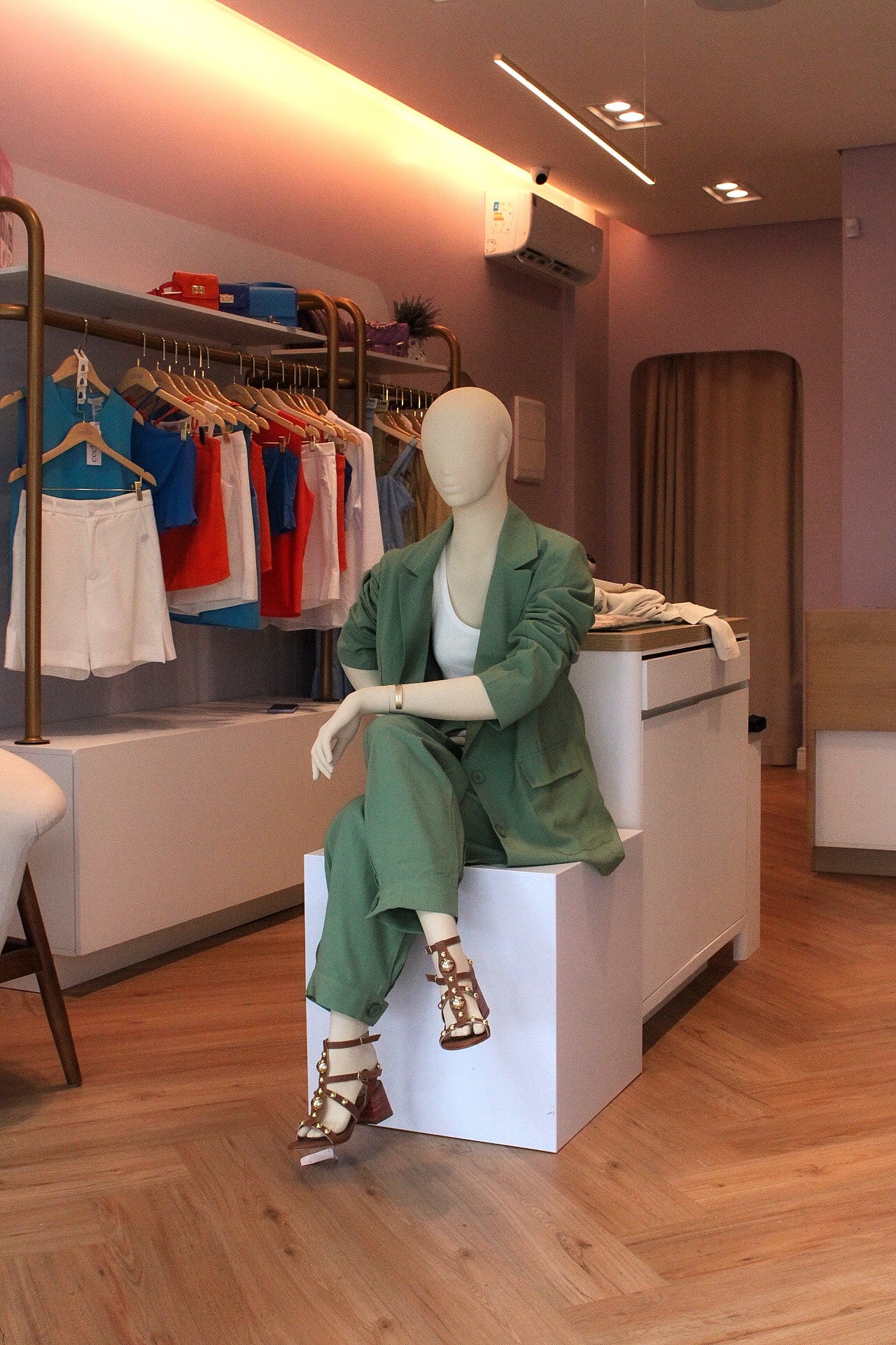 Fachada da boutique com vitrine, manequins e flores suspensas sobre a entrada