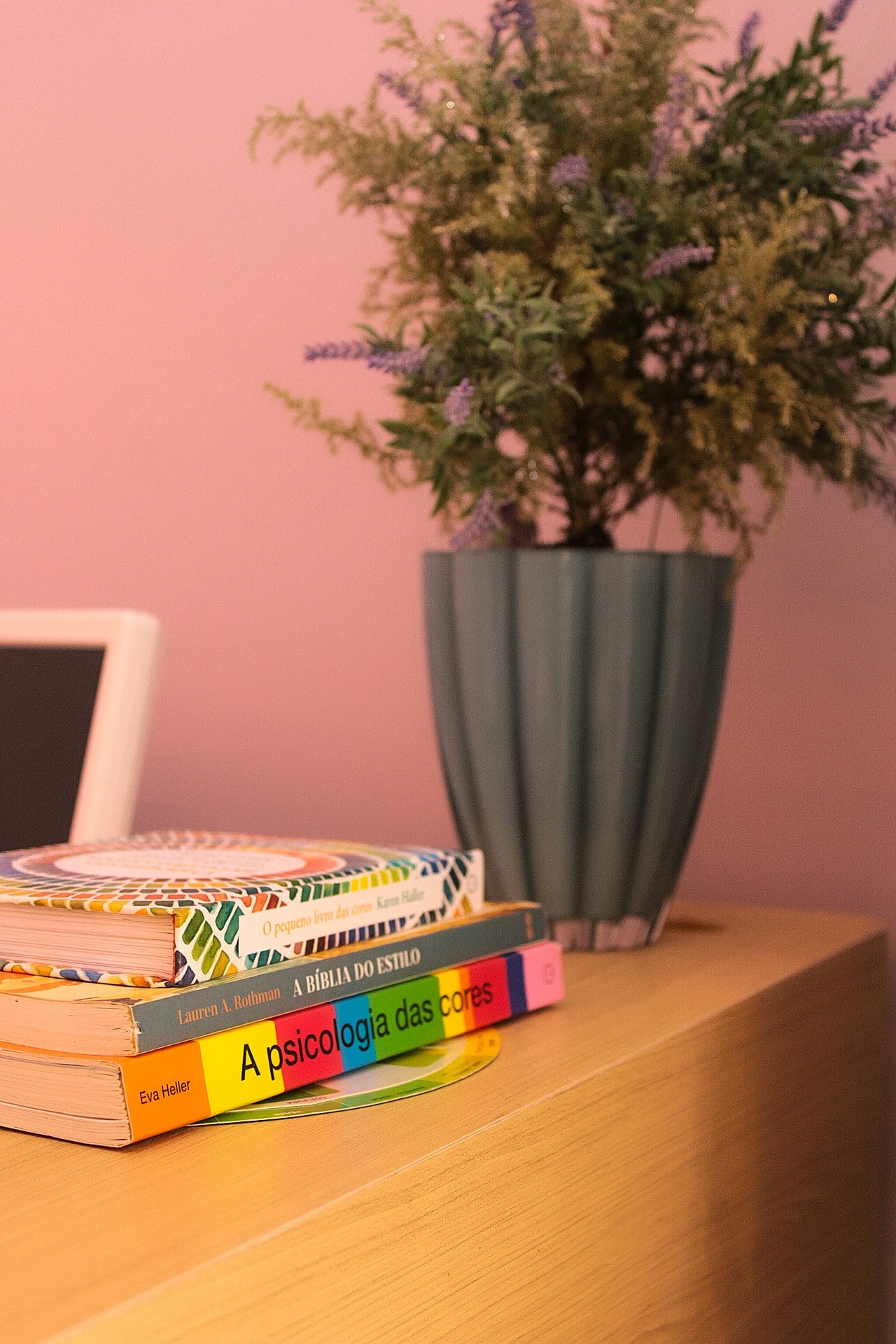 Detalhe do balcão com livros, vaso canelado e arranjo de flores secas