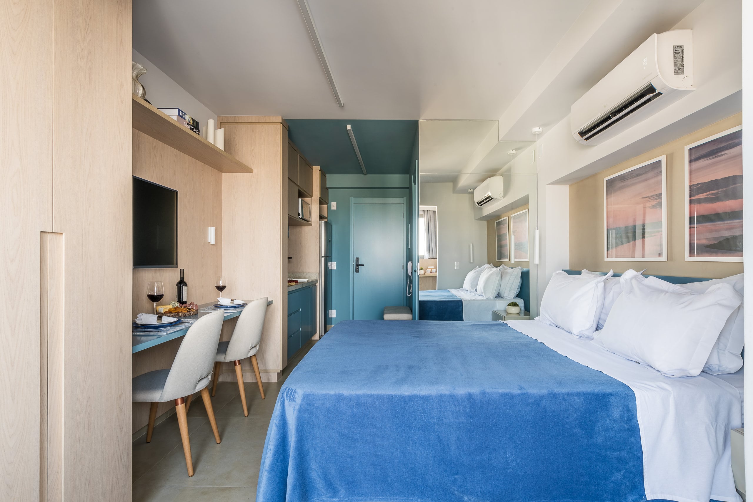 Studio integrado com cama, bancada de refeições e cozinha em azul