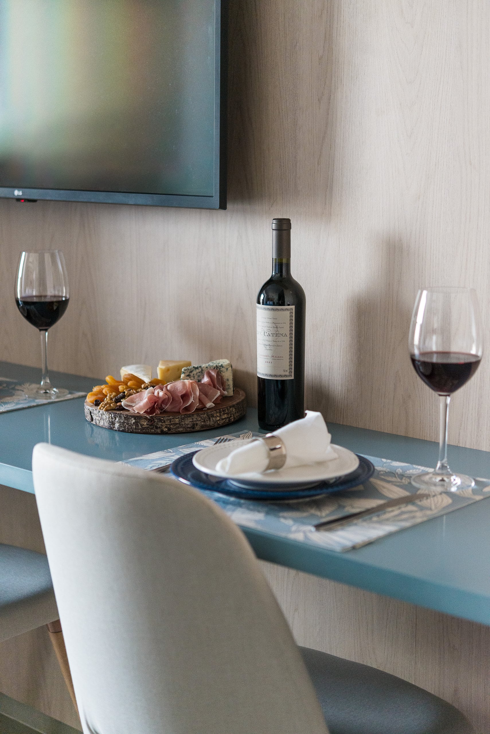 Mesa posta com tábua de frios, vinho e taças sobre a bancada