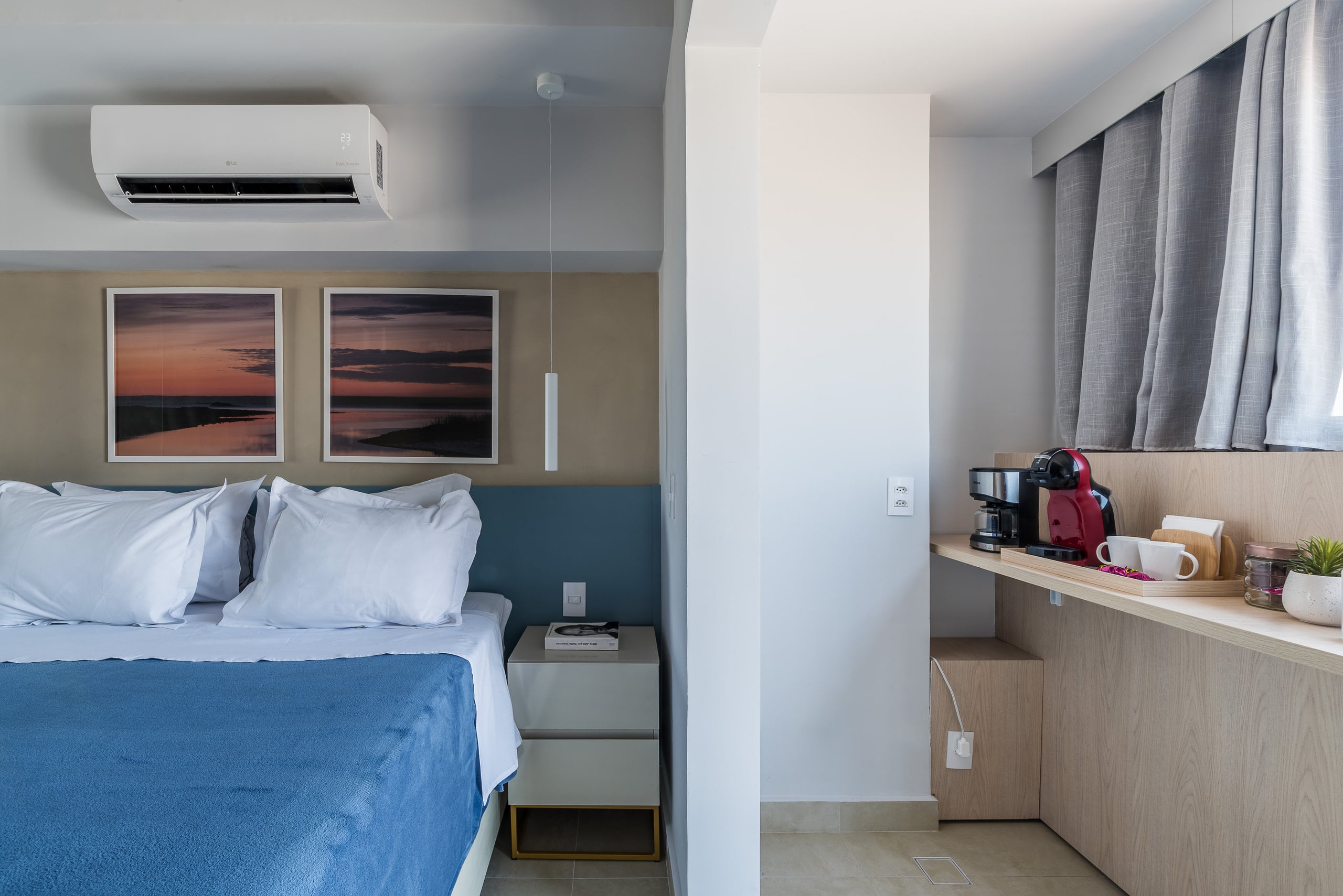 Cama junto à sacada, com a cortina aberta e a cidade ao fundo