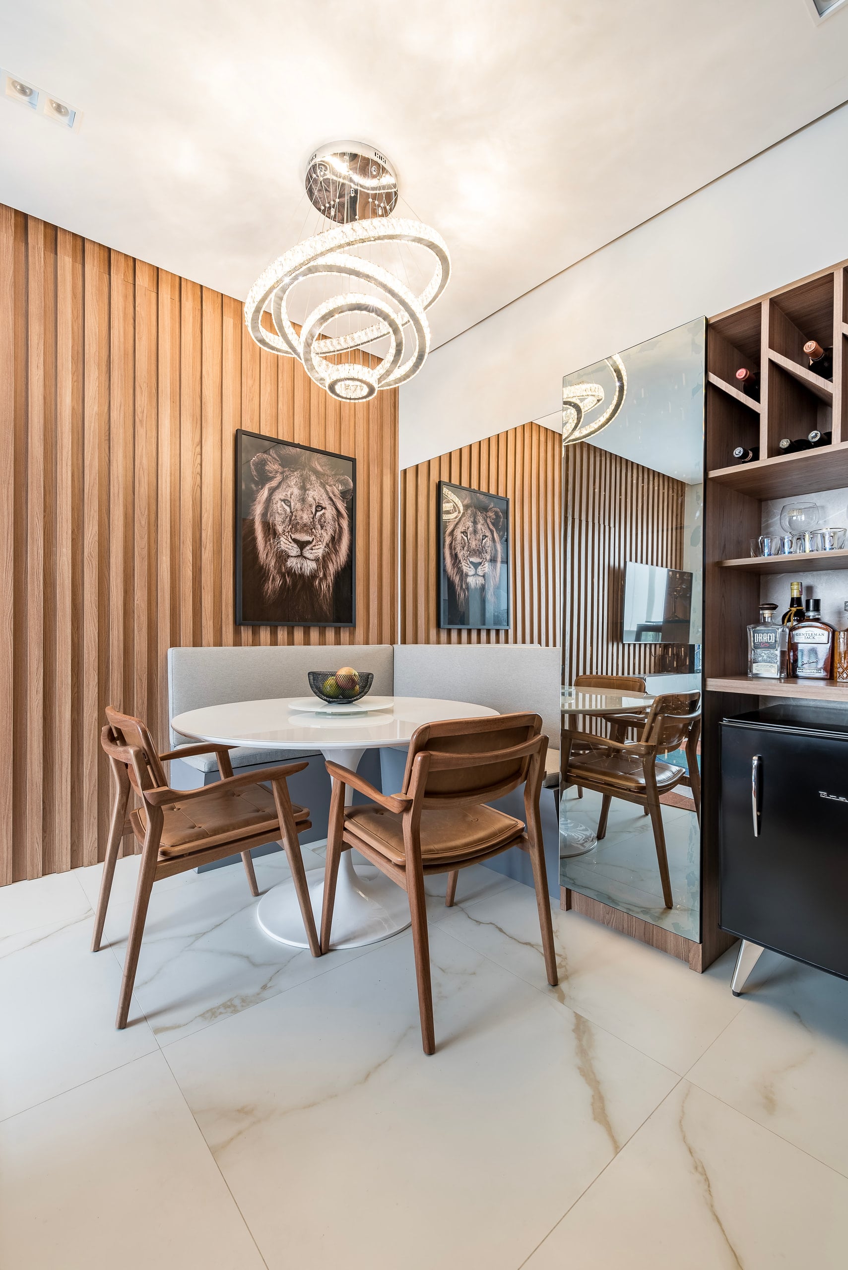 Sala de jantar com painel ripado em madeira, mesa redonda de mármore e adega embutida