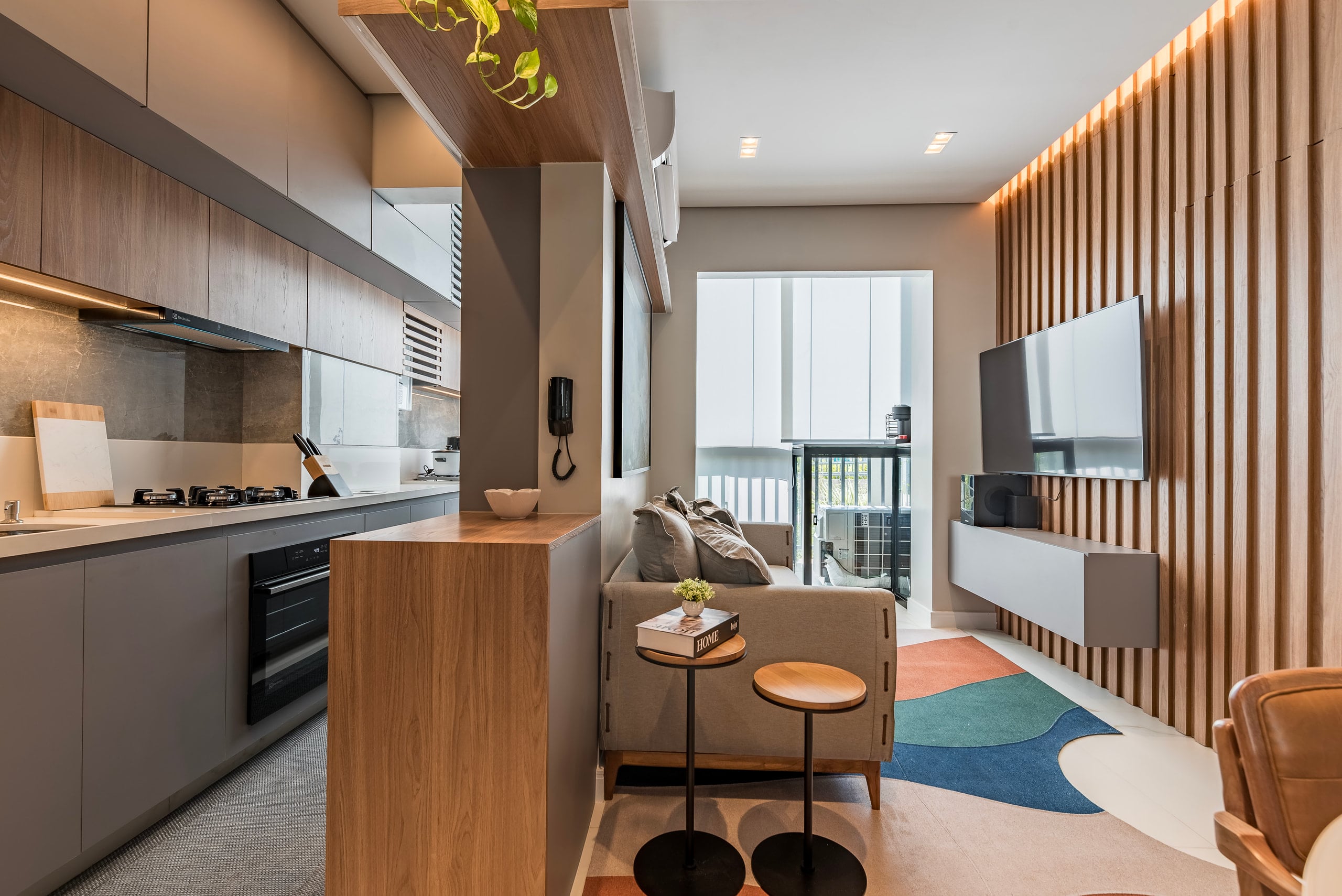 Living integrado com sofá claro, mesa lateral e vista para a varanda