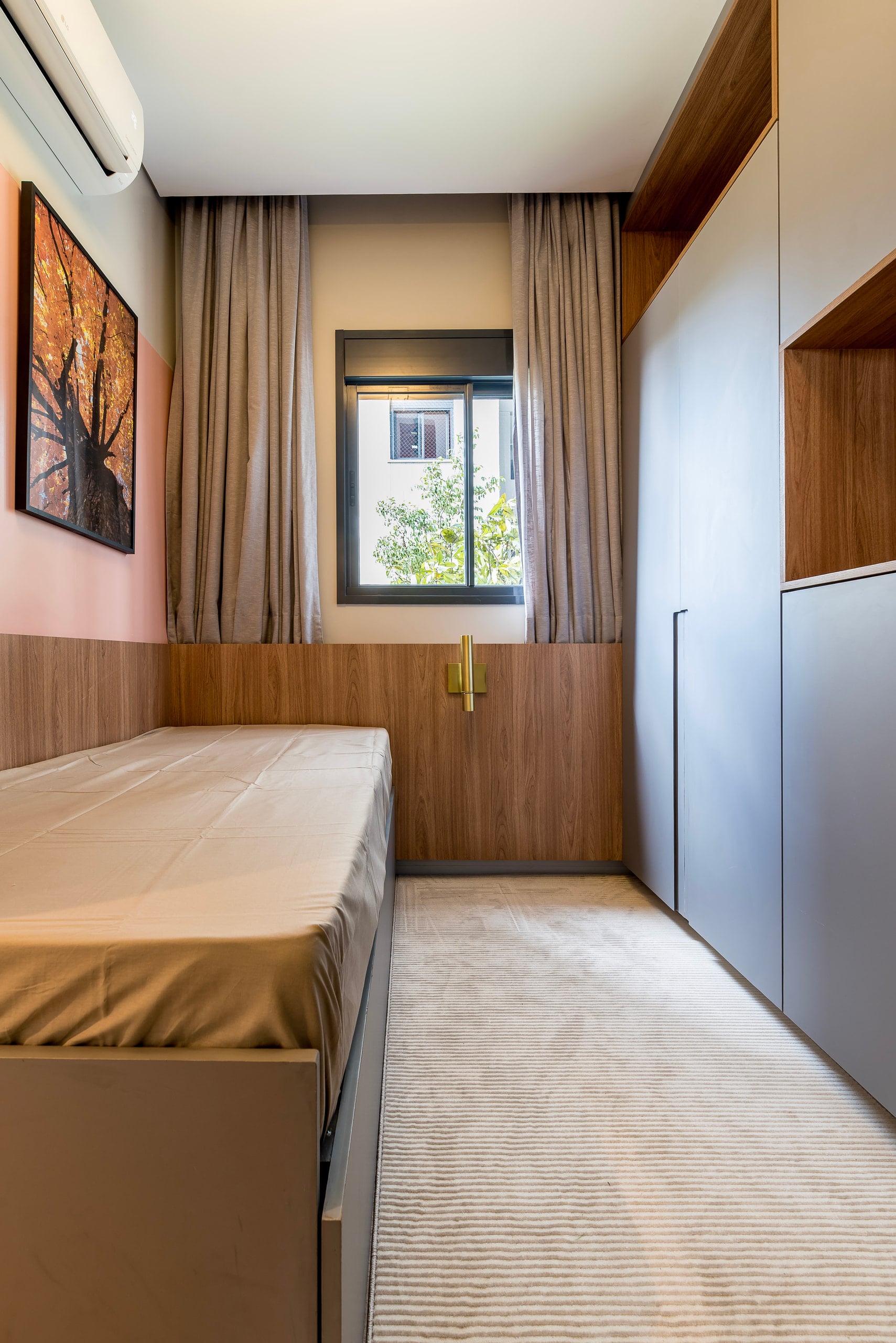 Cama retrátil recolhida na marcenaria, liberando o piso do quarto de hóspedes