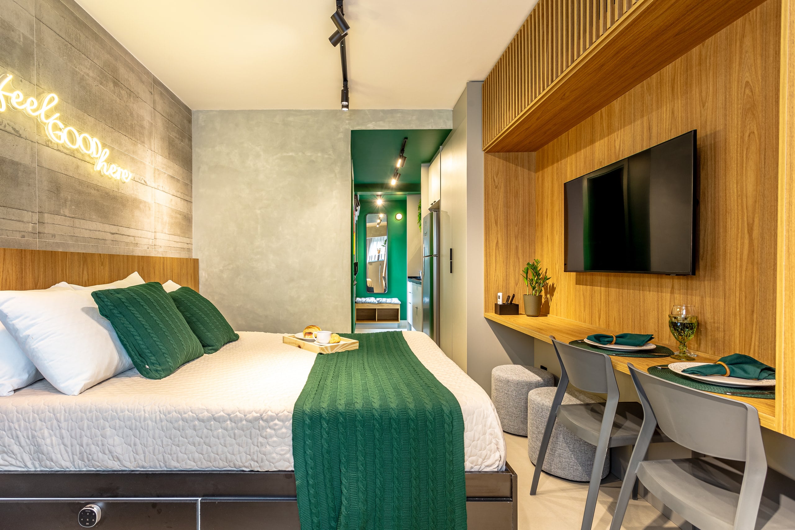 Studio com cama, bancada de refeições e o corredor da cozinha ao fundo
