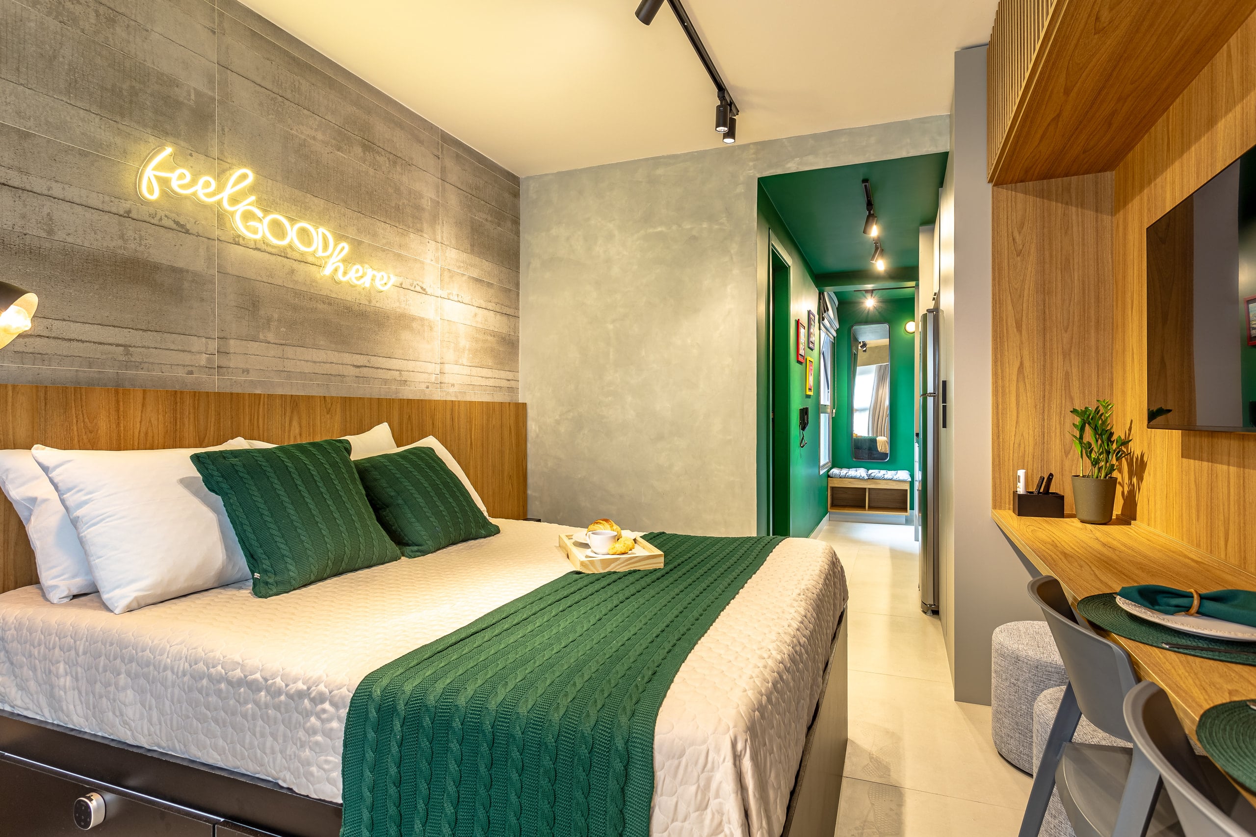 Cama vista de frente, com o letreiro luminoso e o corredor verde ao fundo