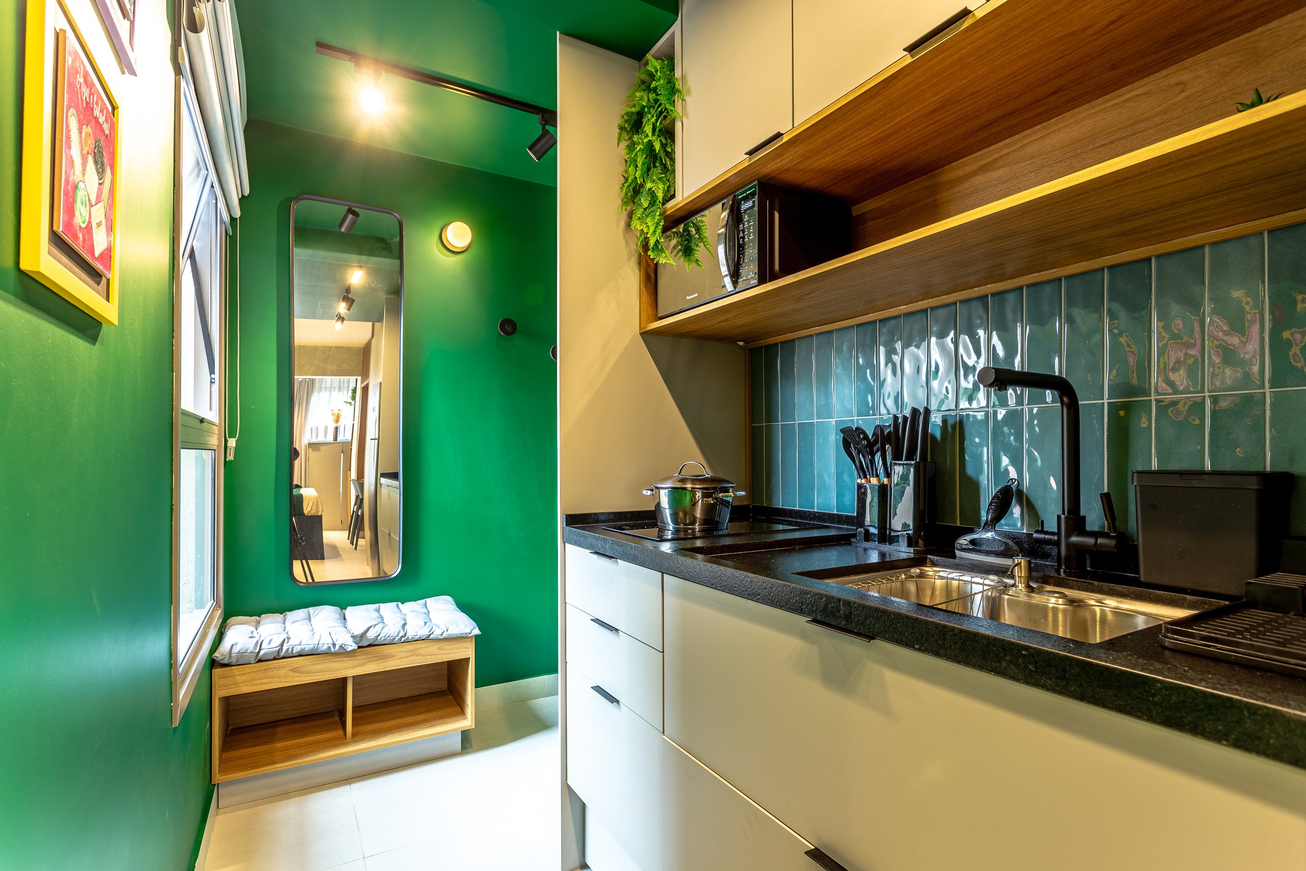 Bancada da cozinha com azulejo azul, cooktop e armários suspensos