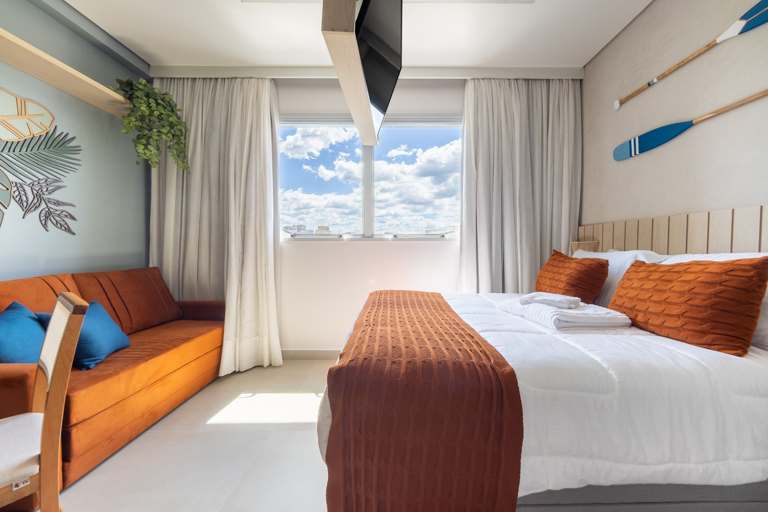 Cama junto à janela, com luz natural e vista para o mar ao fundo
