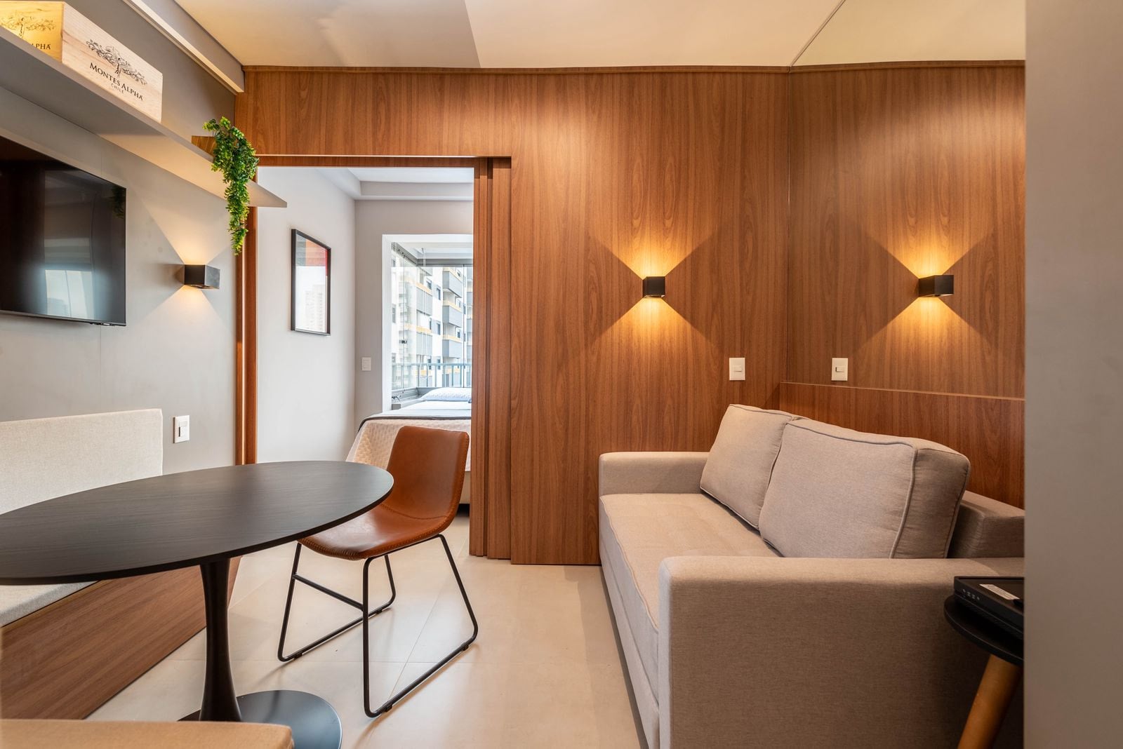 Living integrado com sofá claro, mesa de jantar e painel de madeira