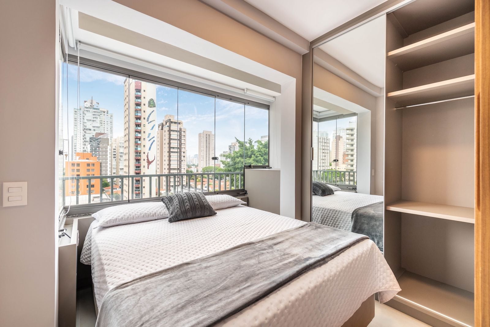 Cama de casal junto à sacada, com vista para a cidade