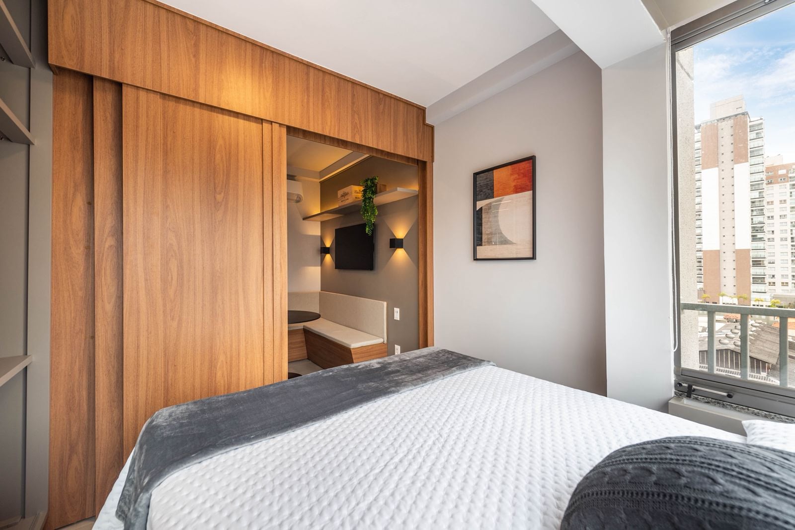 Cama de casal com painel de madeira, quadros e espelho lateral