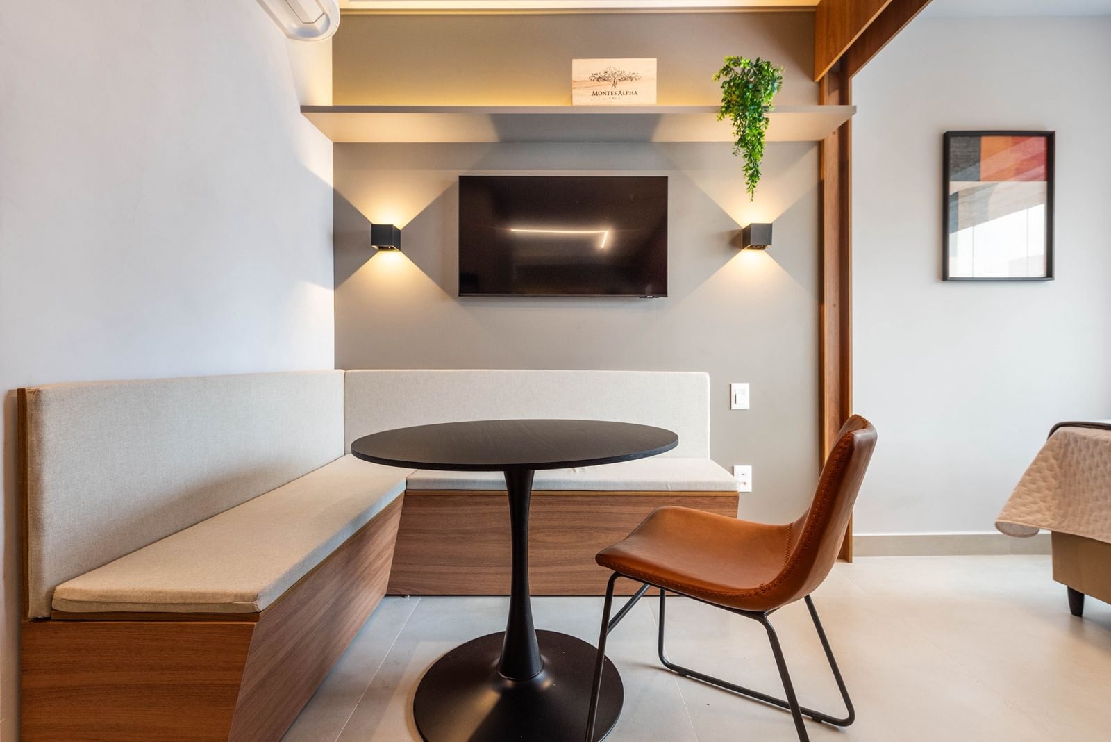 Estar com TV na parede, mesa redonda e banco de madeira