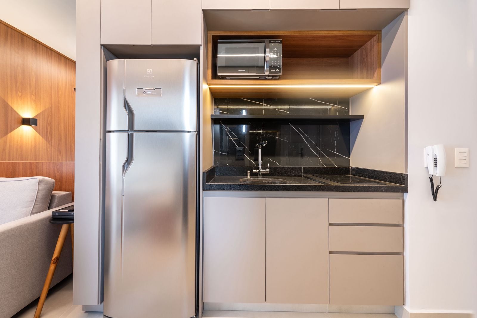 Cozinha com geladeira, micro-ondas e bancada de mármore preto